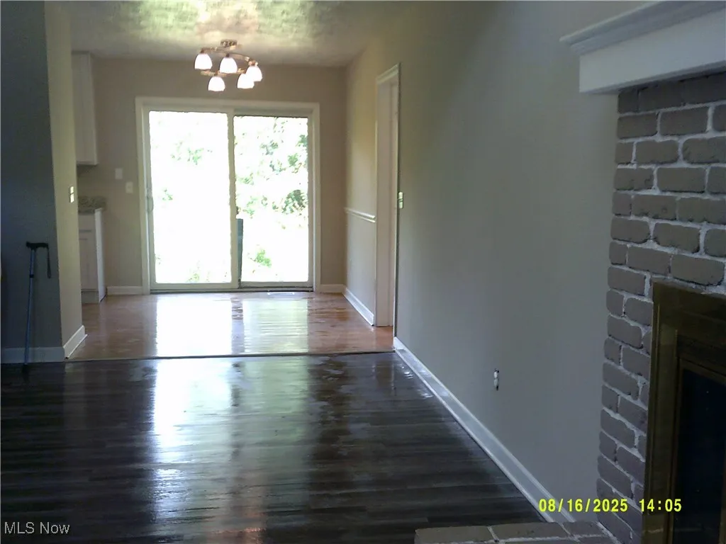 Unfurnished dining area with a fireplace, a chandelier, and dark wood-type flooring