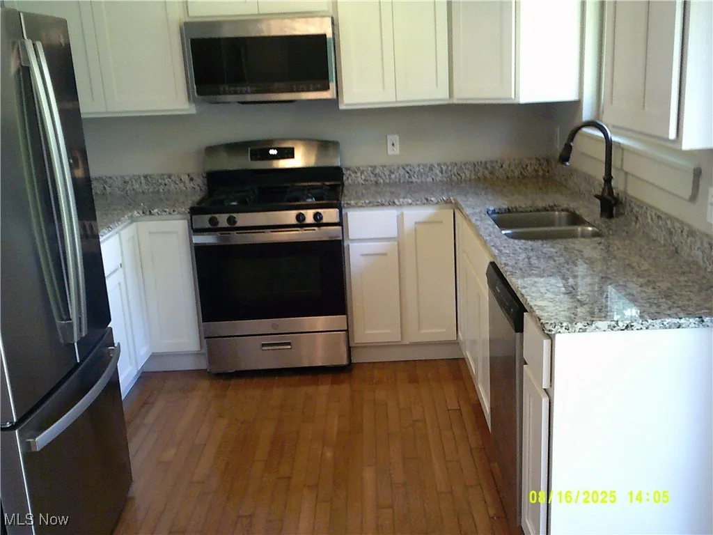 Kitchen with light stone counters, appliances with stainless steel finishes, and white​​‌​​​​‌​​‌‌​‌‌​​​‌‌​‌​‌​‌​​​‌​​ cabinets
