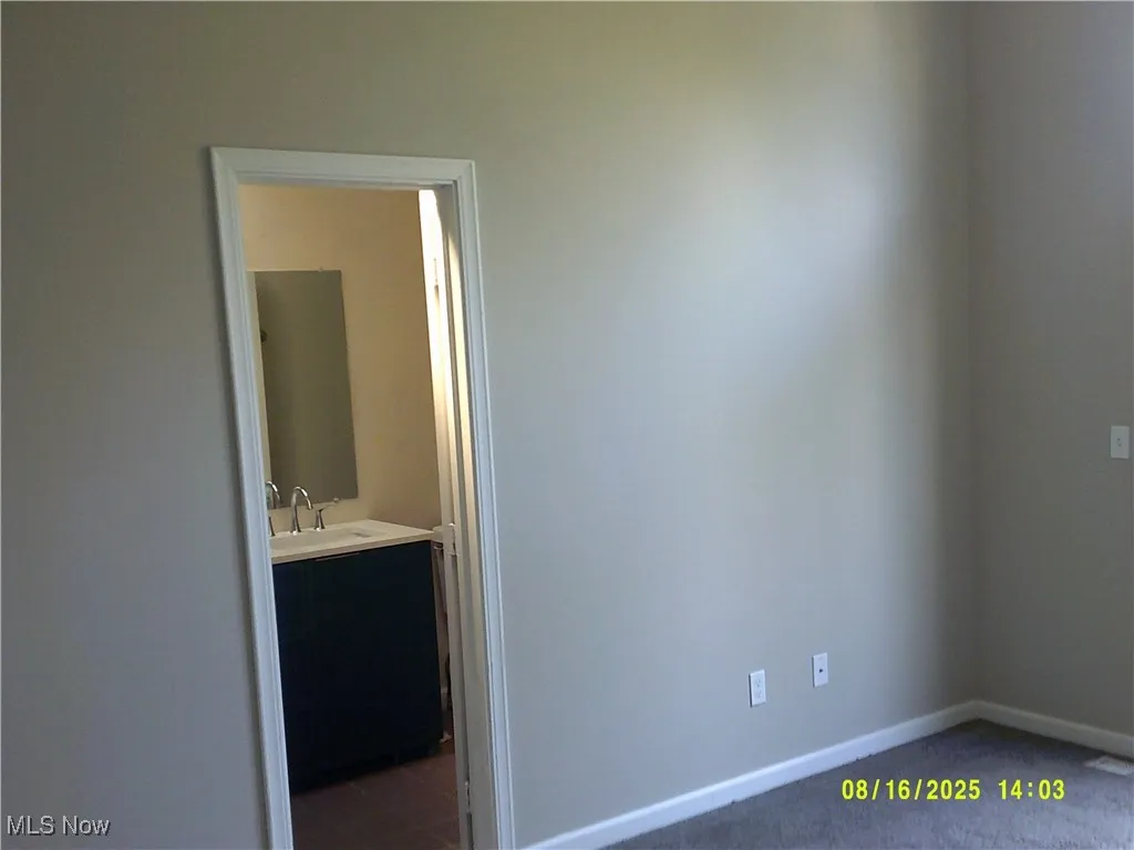 Unfurnished bedroom with dark carpet and ensuite bath