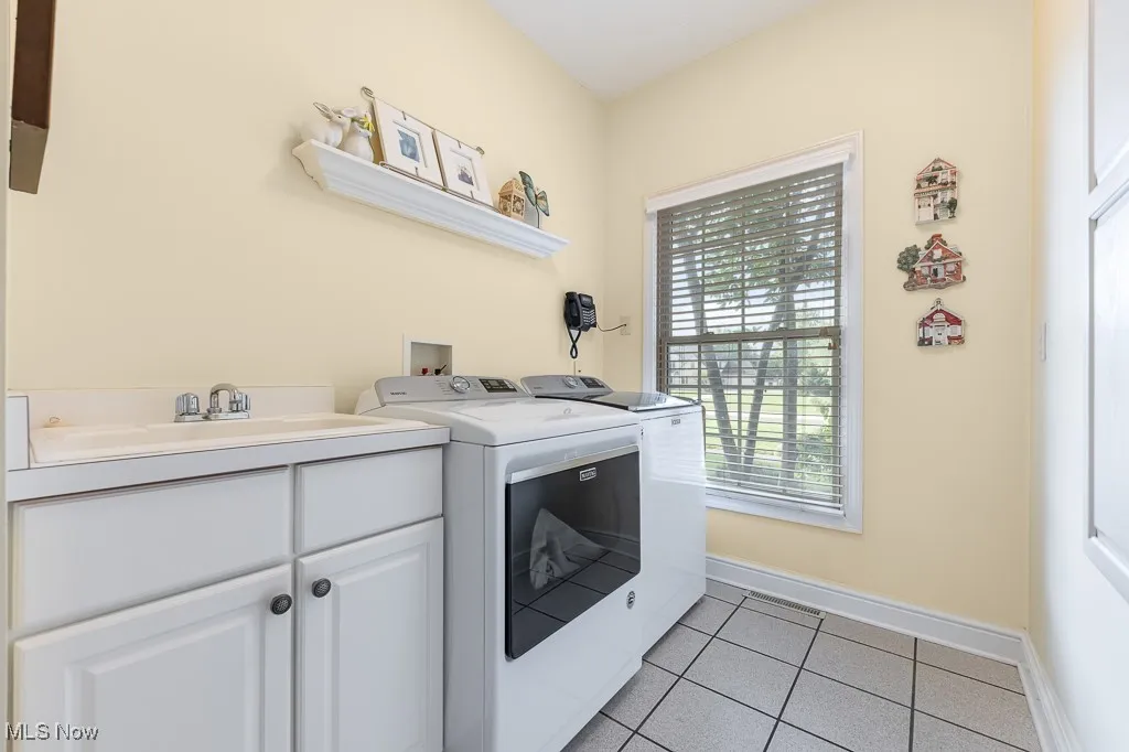 Washroom with light tile patterned flooring, separate washer and dryer, and cabinet space