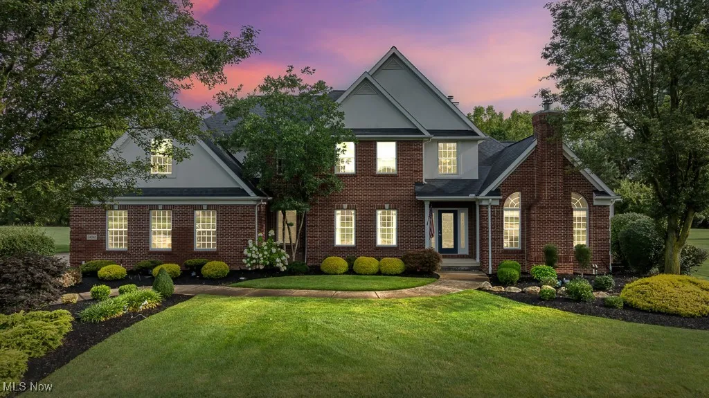 View of front of home with a front yard, brick siding, and a chimney