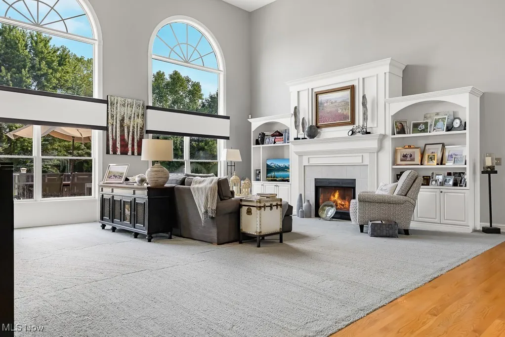 Living area featuring a towering ceiling, wood finished floors, and a tiled fireplace