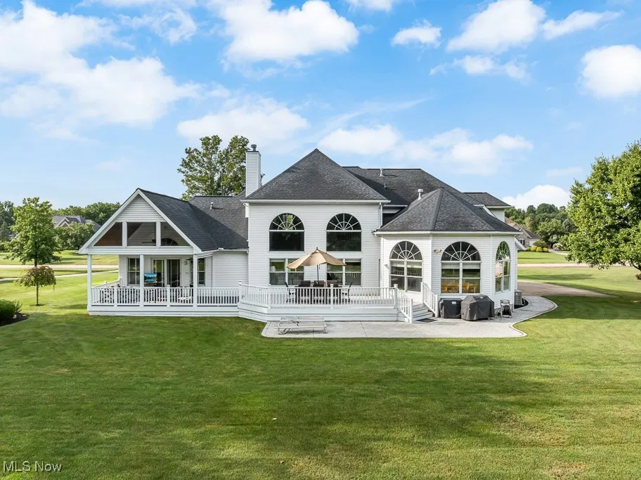Back of property featuring a patio, a yard, a shingled roof, a chimney, and a wooden deck