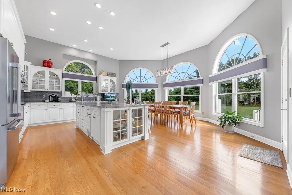Kitchen featuring glass insert cabinets, white cabinets, hanging light fixtures, dark stone counters, and recessed lighting