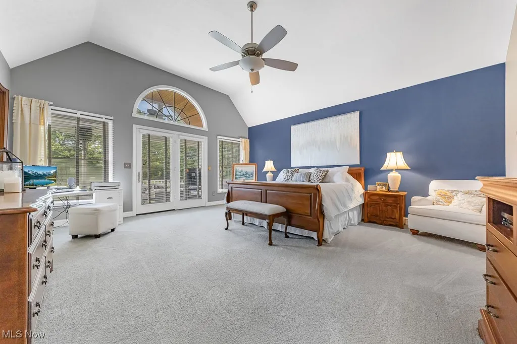 Bedroom with light colored carpet, access to exterior, high vaulted ceiling, and ceiling fan