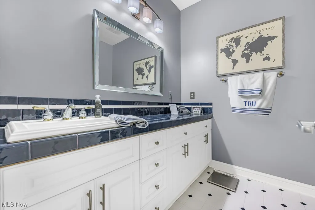 Bathroom with double vanity and light tile patterned floors