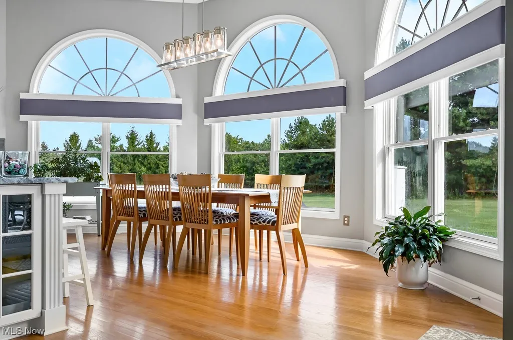 Dining area with light wood finished floors, wine cooler, and a high ceiling