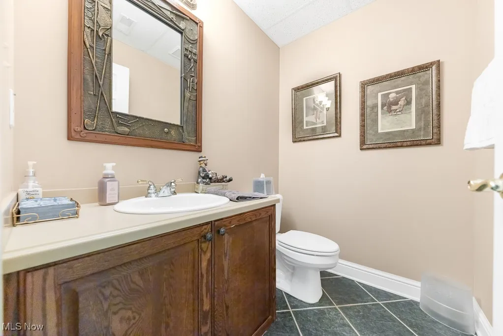 Half bath featuring dark tile patterned flooring and vanity