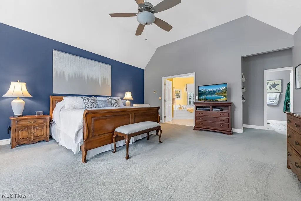 Bedroom with light colored carpet, a ceiling fan, and vaulted ceiling