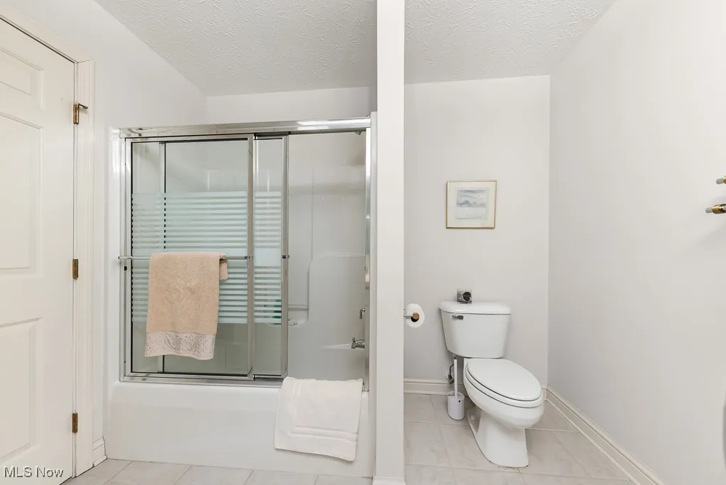 Full bath with tile patterned flooring and a textured ceiling