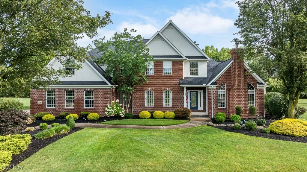 View of front facade with a front lawn, brick siding, and a chimney