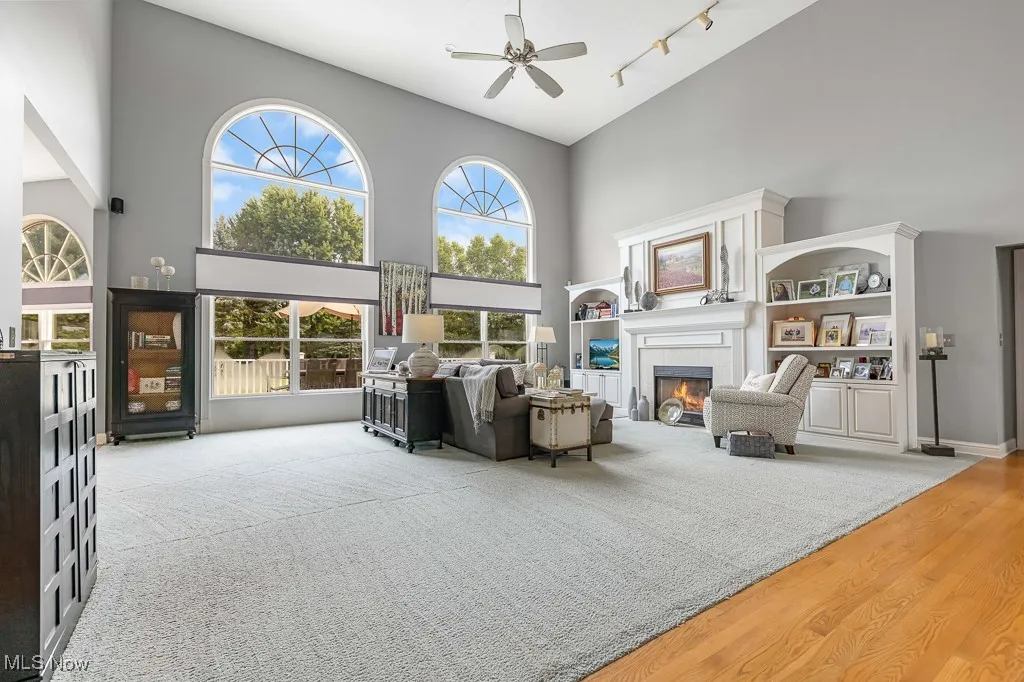 Living area with a high ceiling, a fireplace, wood finished floors, a ceiling fan, and track lighting