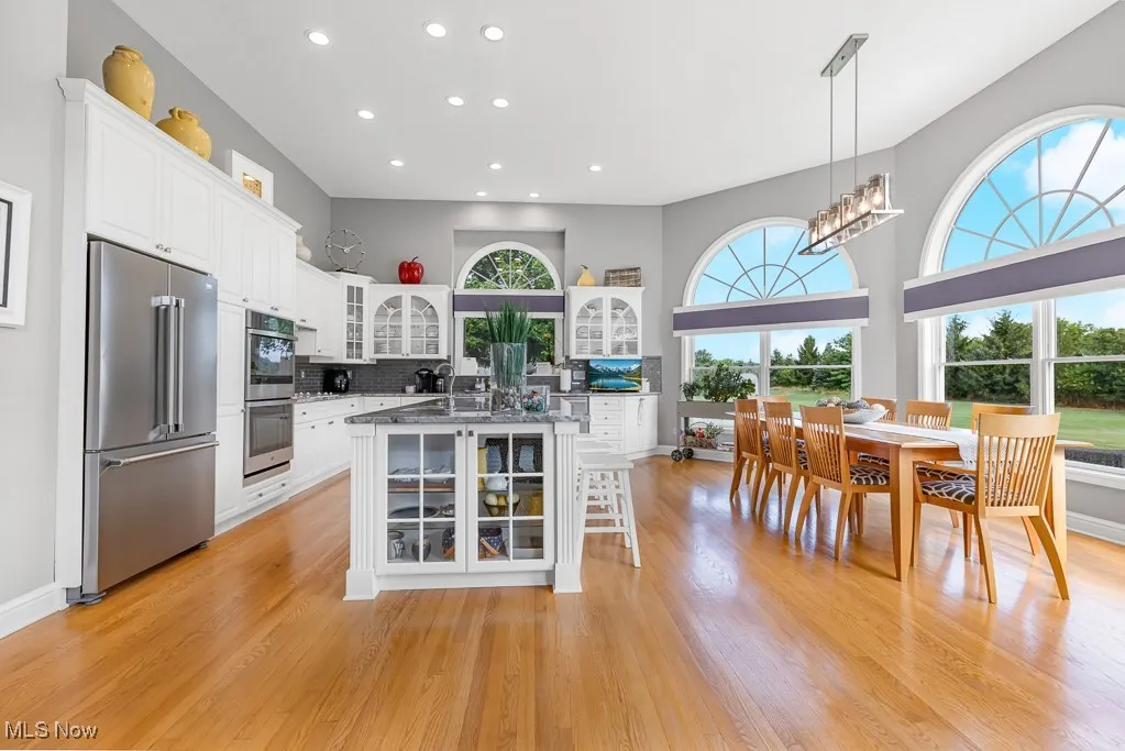 Kitchen featuring glass insert cabinets, stainless steel appliances, decorative light fixtures, white cabinets, and recessed lighting