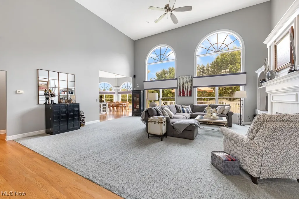 Living area with plenty of natural light, wood finished floors, a high ceiling, and ceiling fan