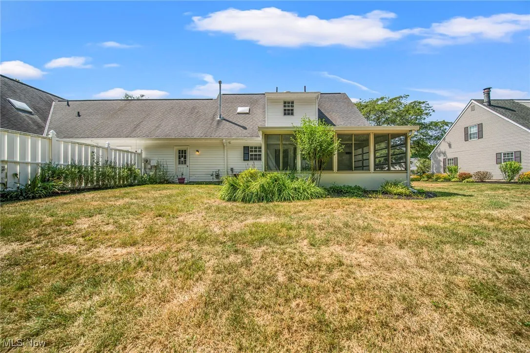 Rear view of property featuring a yard, a sunroom, and roof with shingles