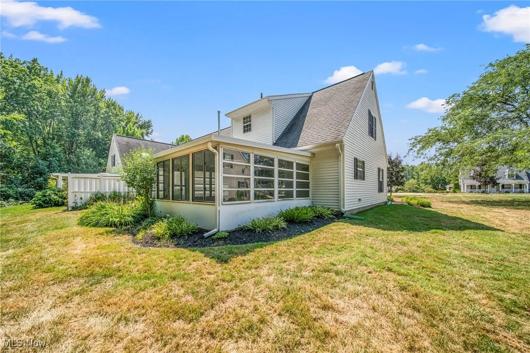 Rear view of house with a sunroom, a lawn, and a shingled roof