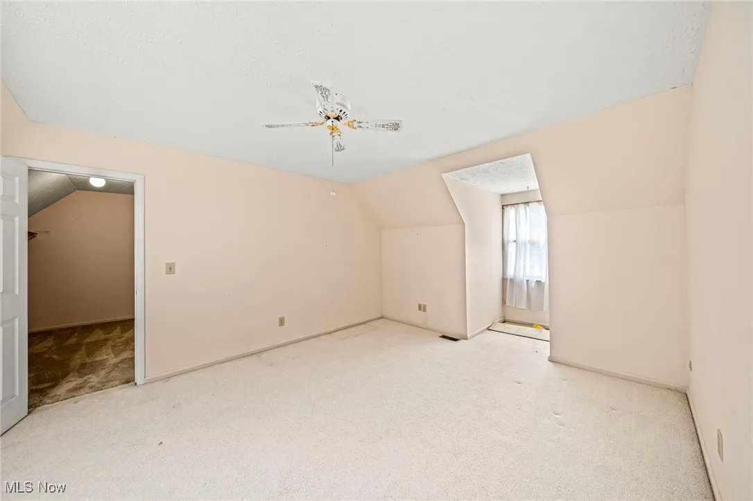 Bonus room featuring vaulted ceiling, a textured ceiling, carpet, and a ceiling fan