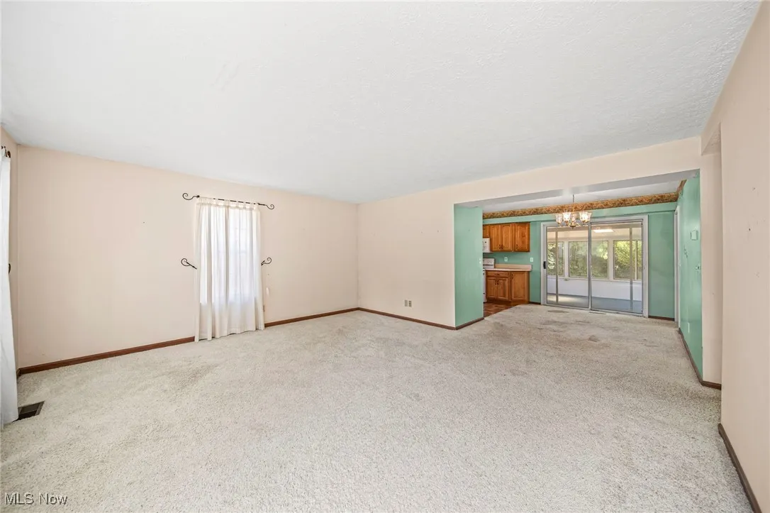 Empty room featuring a chandelier and light carpet