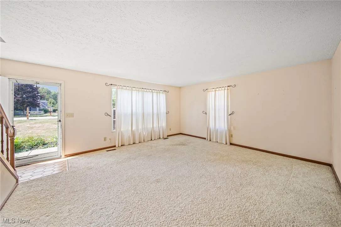 Unfurnished living room featuring a textured ceiling and carpet flooring