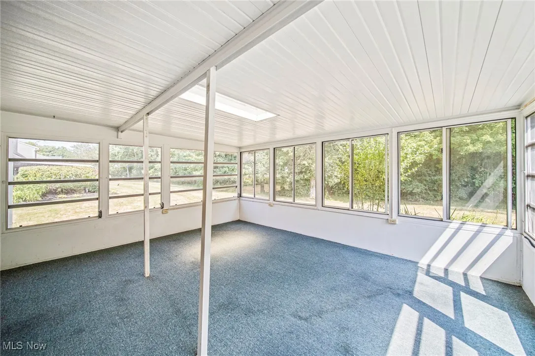 Unfurnished sunroom featuring a skylight