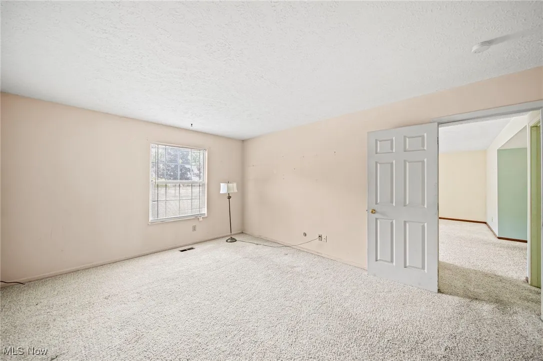 Carpeted empty room with a textured ceiling and baseboards