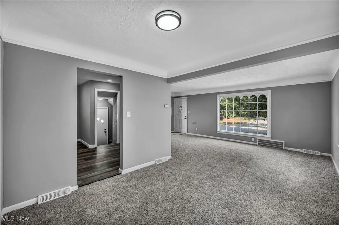Carpeted spare room with a textured ceiling and ornamental molding