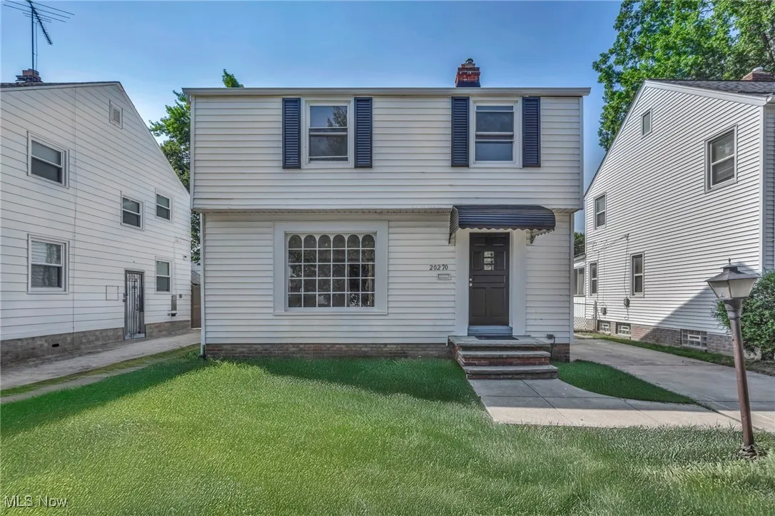Colonial-style house featuring a chimney and a front lawn