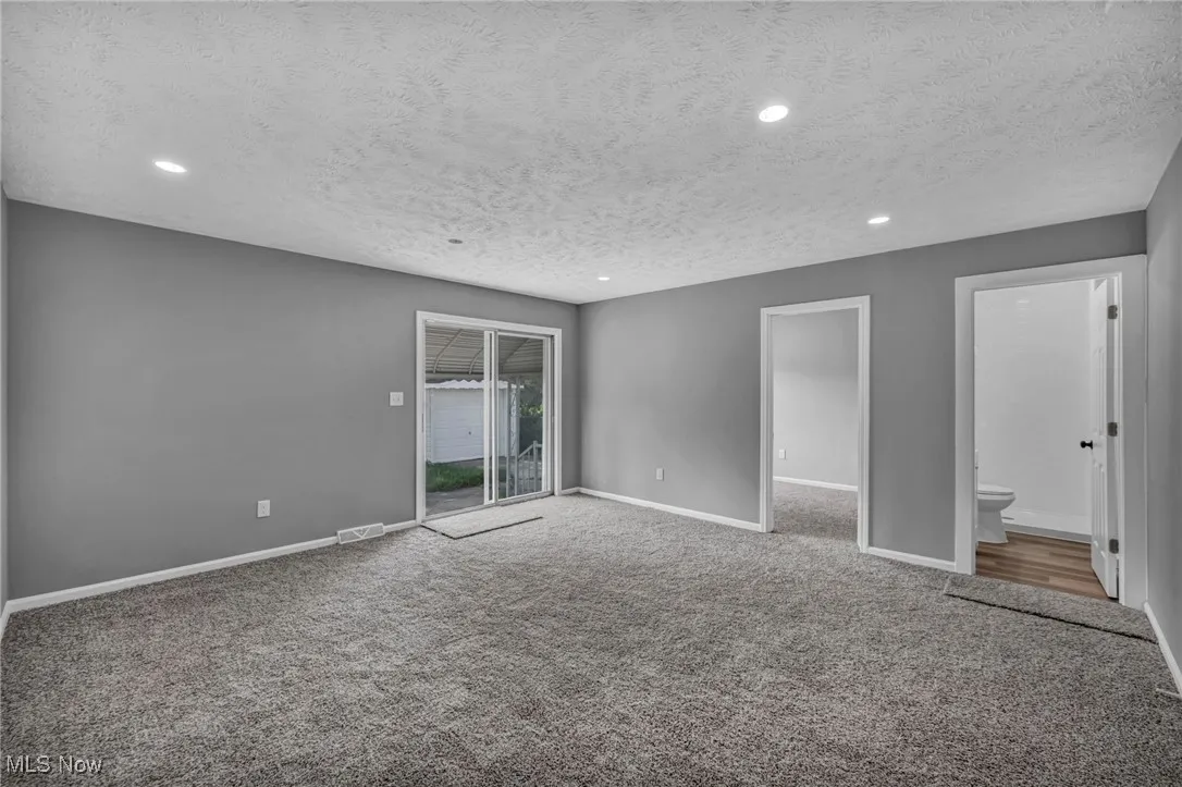Unfurnished bedroom featuring access to outside, carpet flooring, a textured ceiling, recessed lighting, and ensuite bath