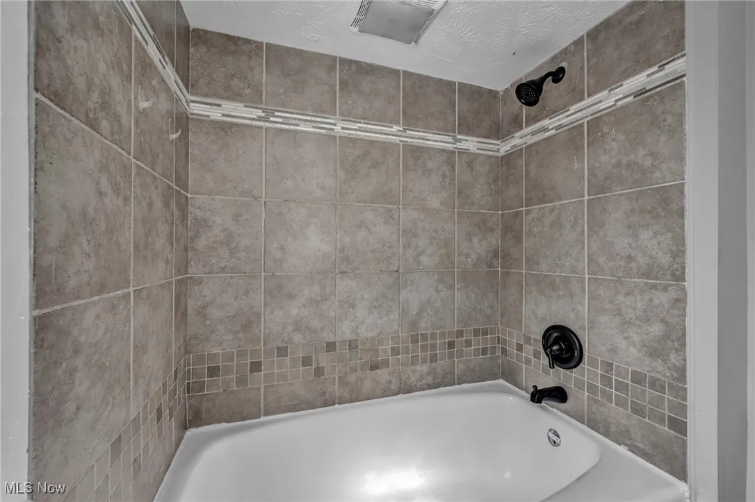 Full bath with  shower combination and a textured ceiling