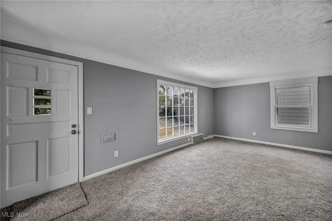 Carpeted empty room with baseboards and a textured ceiling