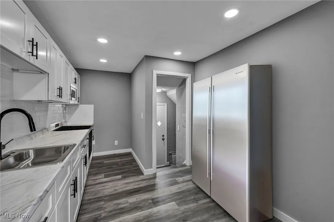 Kitchen featuring stainless steel appliances, white cabinets, backsplash, dark wood-style floors, and recessed lighting
