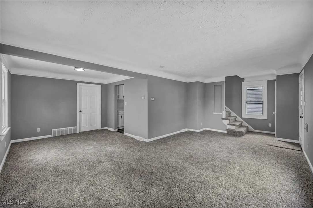 Basement with stairway, carpet, a textured ceiling, and ornamental molding