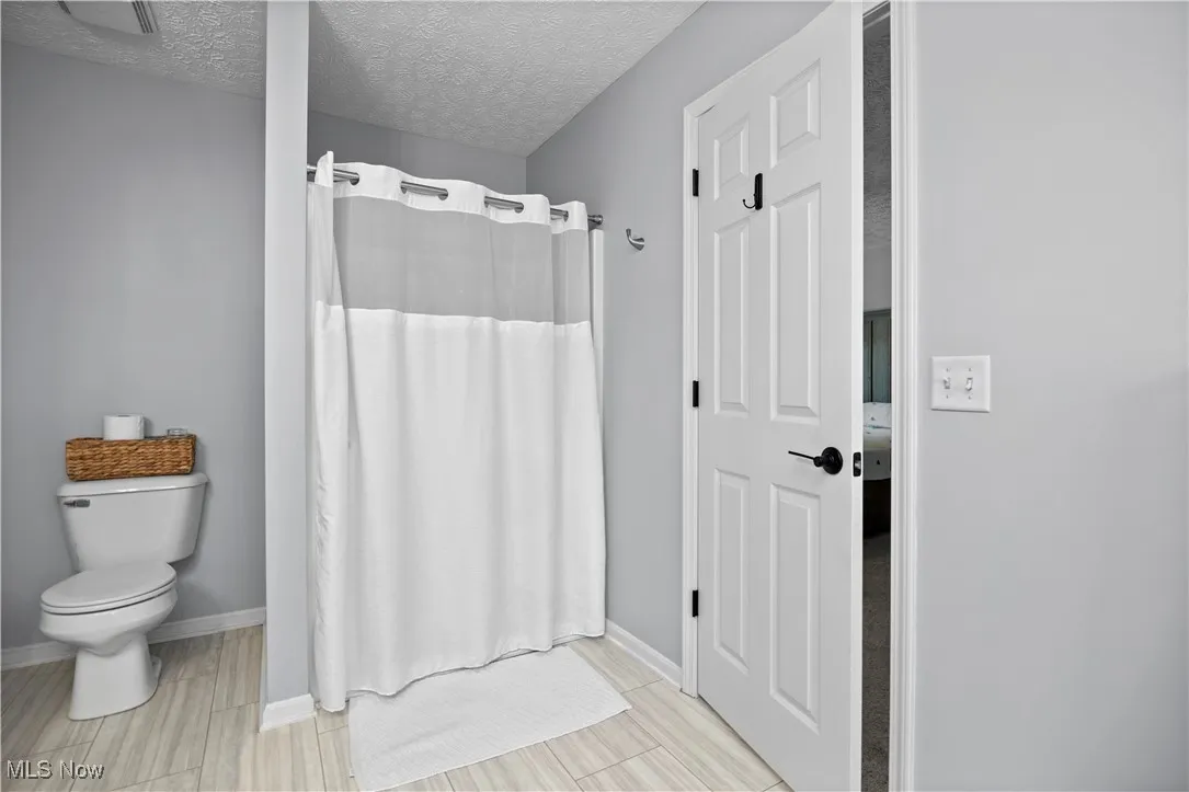 Full bathroom featuring a textured ceiling, a shower stall, and wood finish floors