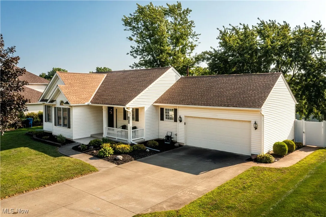 View of front of property featuring a garage, driveway, a porch, and roof with shingles