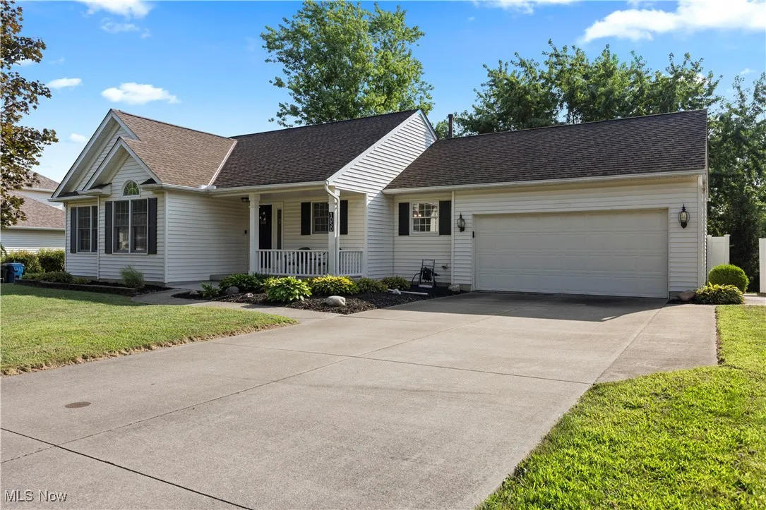 Single story home featuring roof with shingles, an attached garage, a porch, a front yard, and concrete driveway