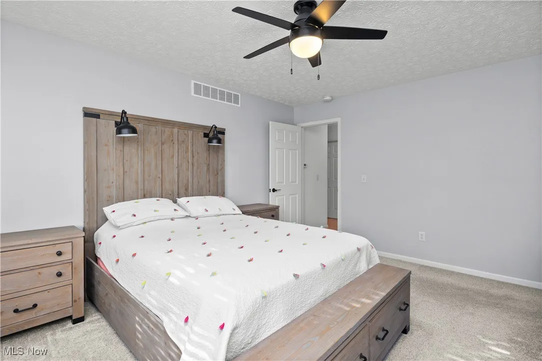 Bedroom with light carpet, a textured ceiling, and ceiling fan
