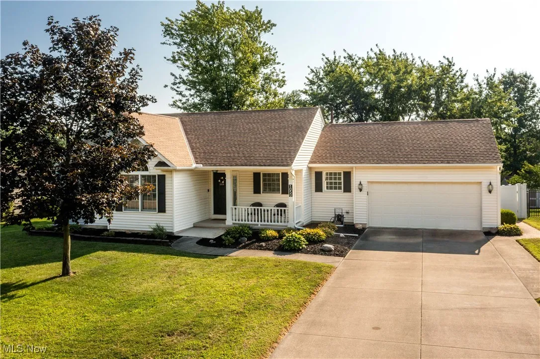View of front facade featuring driveway, a porch, a garage, and a front lawn