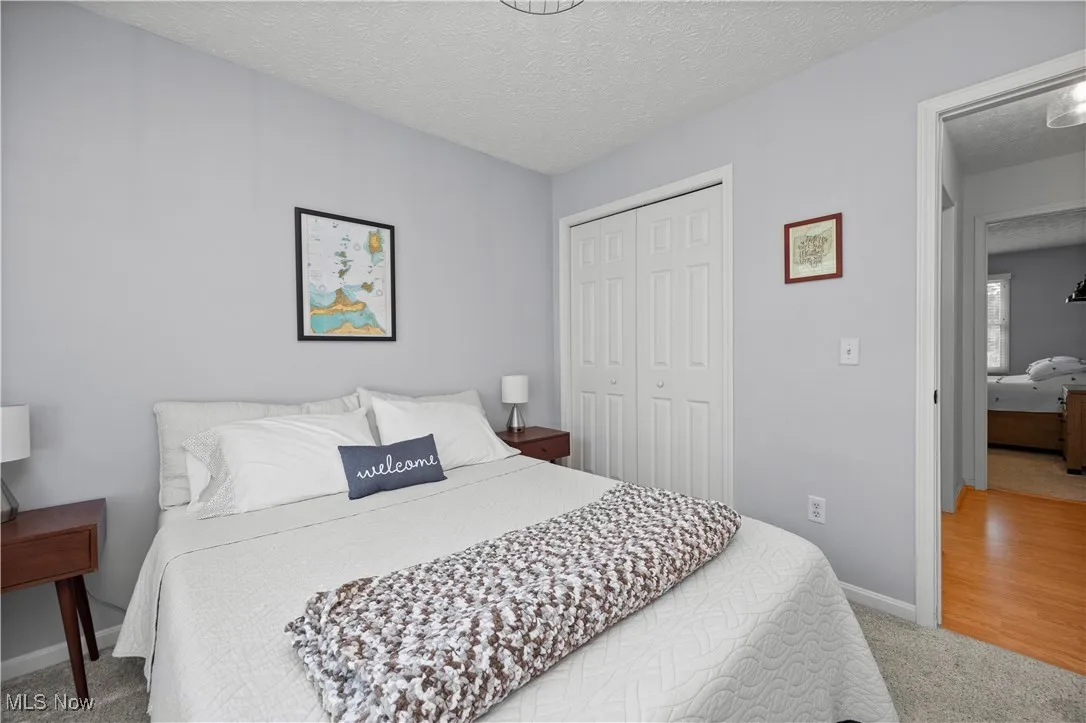 Bedroom featuring a textured ceiling, light colored carpet, and a closet