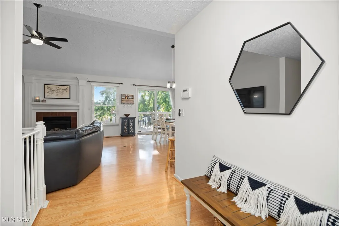 Hallway featuring lofted ceiling, a textured ceiling, and light wood-style floors