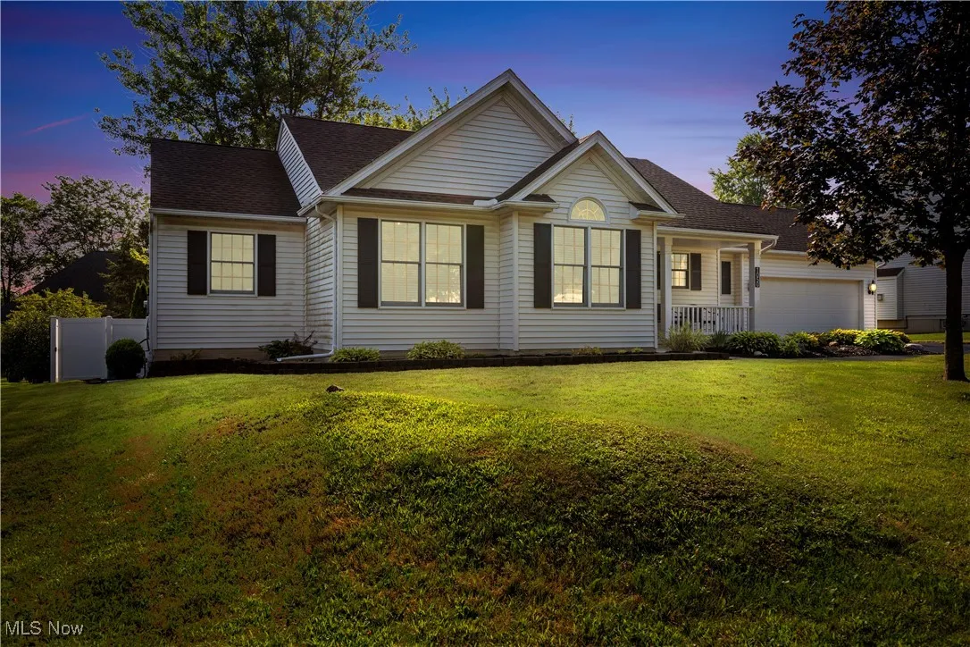 Ranch-style home with a porch, a shingled roof, and a garage