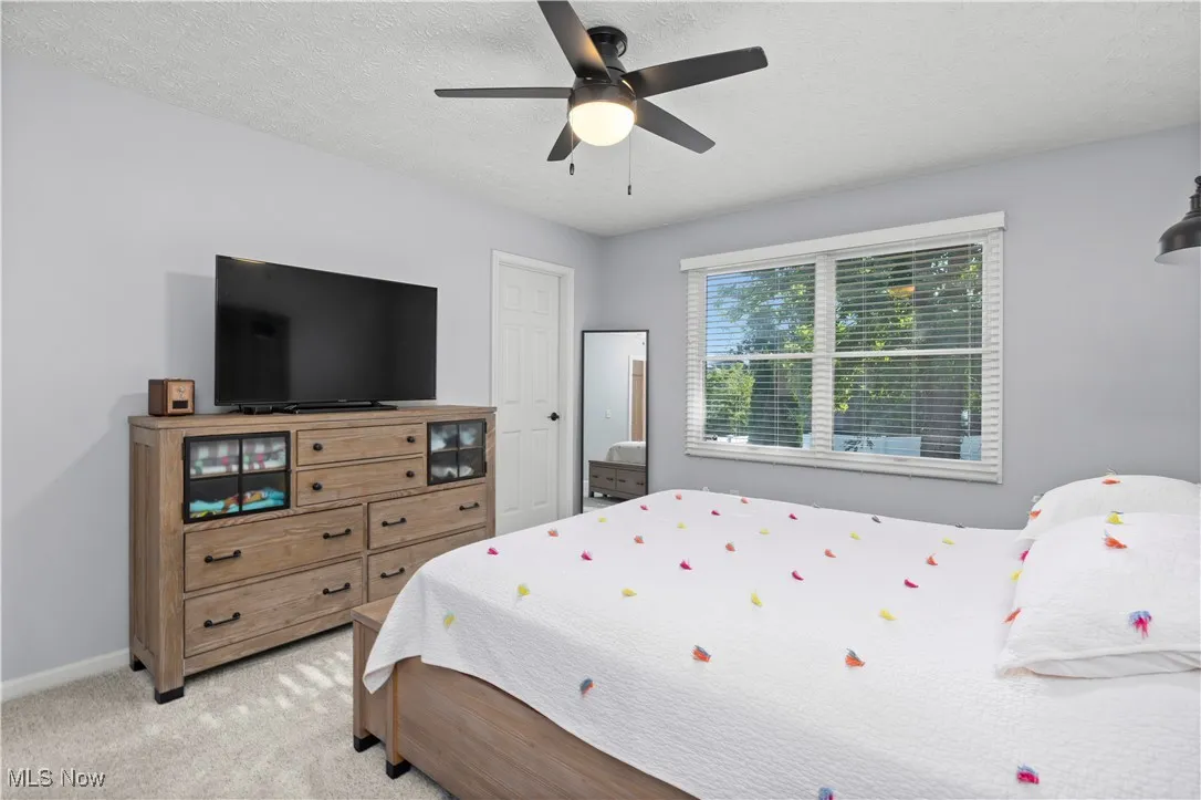 Bedroom with a textured ceiling, light carpet, and a ceiling fan