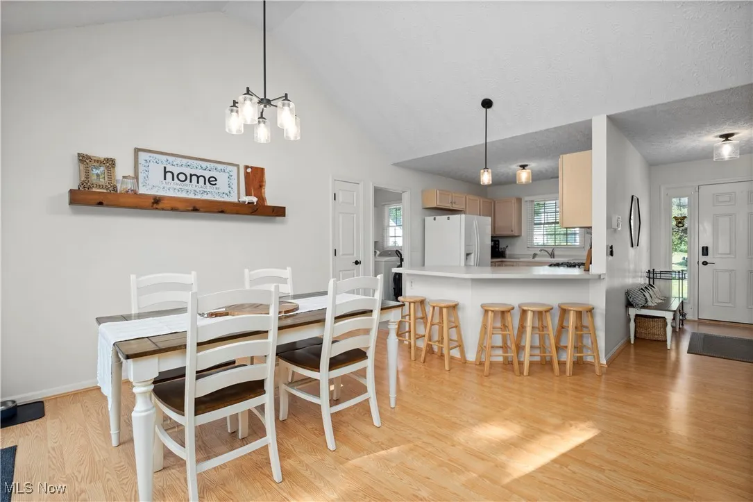 Dining area with light wood-style floors and high vaulted ceiling