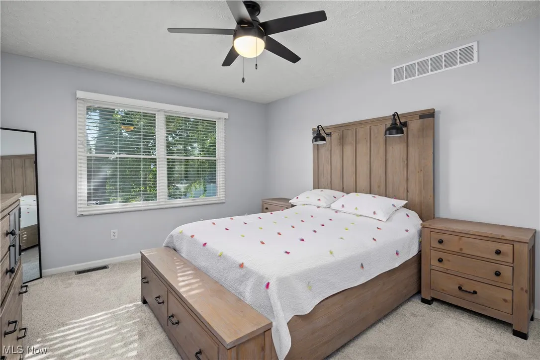 Bedroom with a textured ceiling, carpet flooring, and a ceiling fan