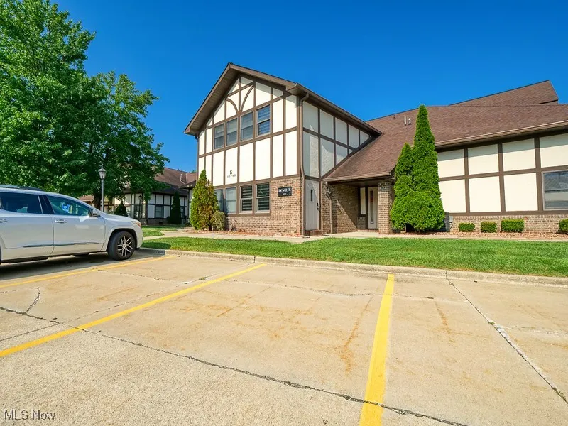 View of front of property featuring brick siding, uncovered parking, and a front yard
