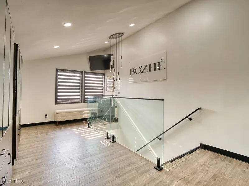 Stairs featuring vaulted ceiling, wood style floors, and recessed lighting