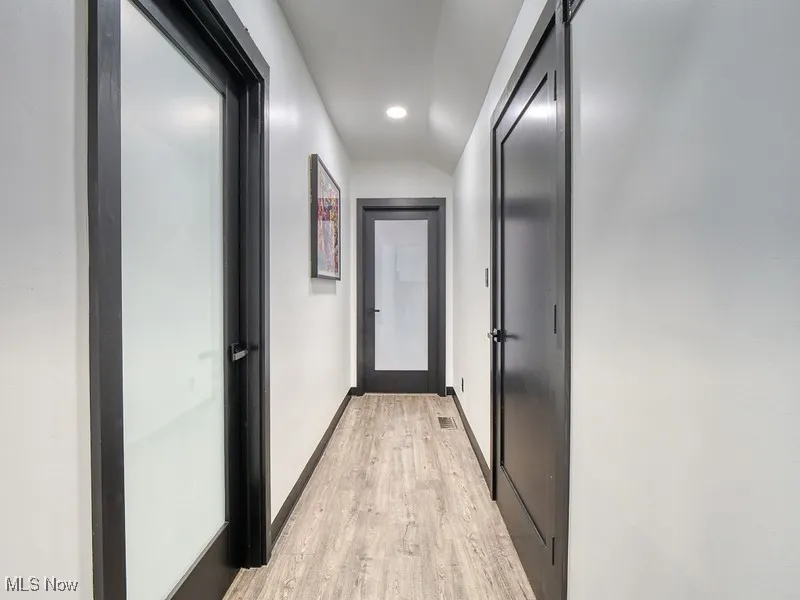 Corridor featuring light wood-type flooring, recessed lighting, and vaulted ceiling