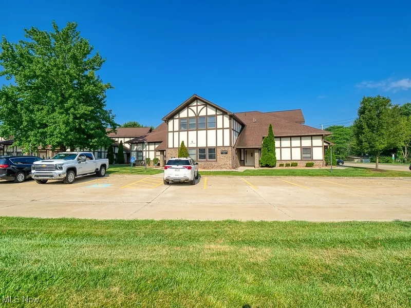 English style home featuring brick siding, a front lawn, and uncovered parking