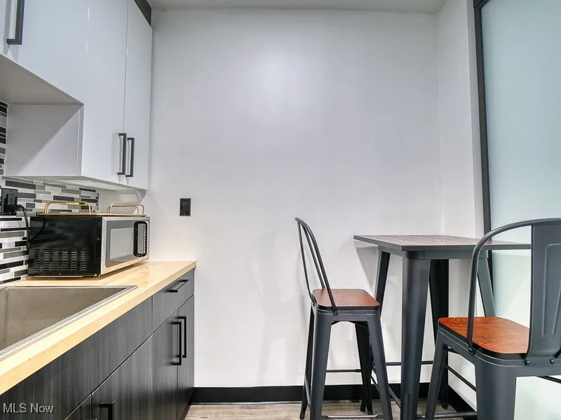 Kitchen featuring stainless steel microwave, gray cabinets, white cabinets, modern cabinets, and decorative backsplash