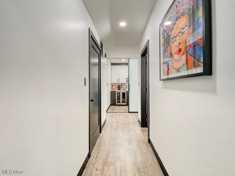 Corridor with light wood-type flooring, recessed lighting, and beverage cooler