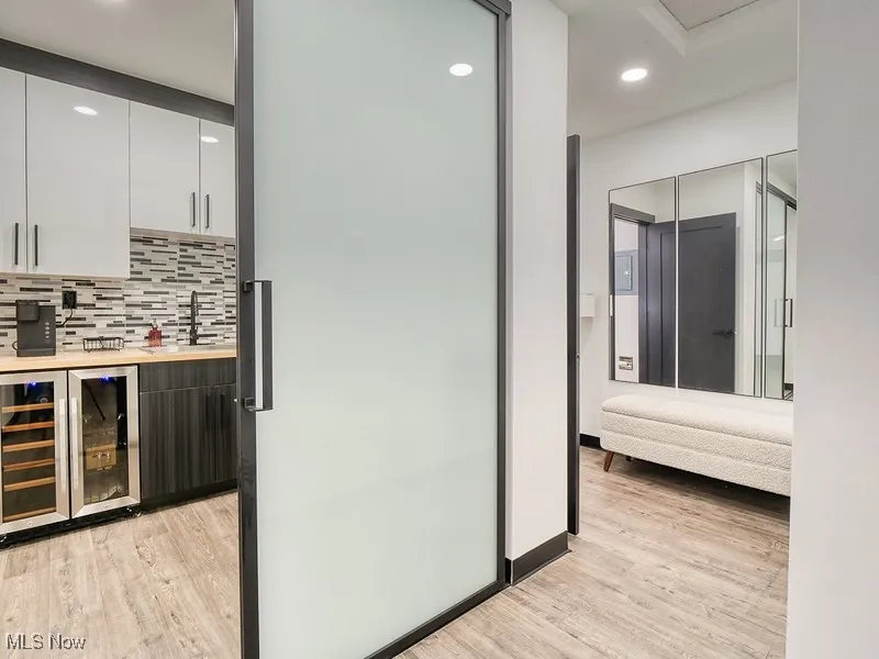Indoor bar featuring white cabinetry, beverage cooler, decorative backsplash, modern cabinets, and recessed lighting